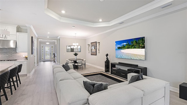 living room featuring a tray ceiling, light wood-type flooring, visible vents, and baseboards