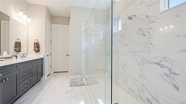 bathroom with marble finish floor, a marble finish shower, baseboards, and vanity