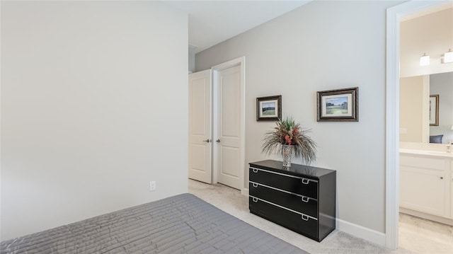 bedroom with light carpet, baseboards, and ensuite bathroom