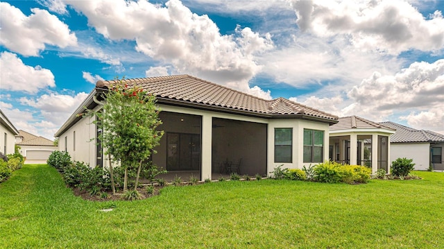 back of house with a sunroom, a tiled roof, a lawn, and stucco siding