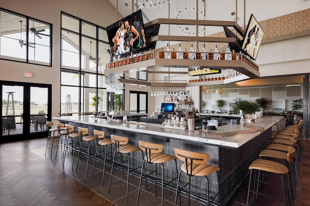 community bar area featuring a towering ceiling, a ceiling fan, and french doors
