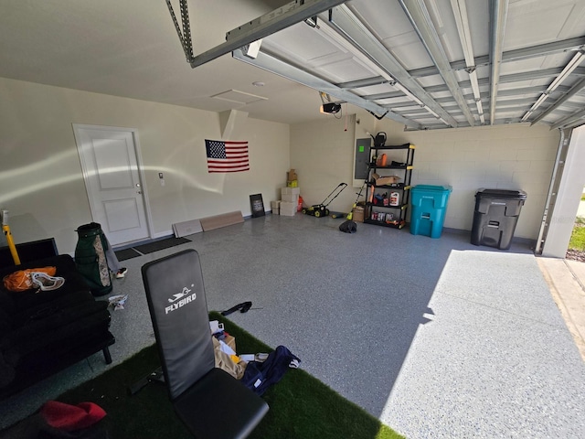 garage with concrete block wall, electric panel, and a garage door opener