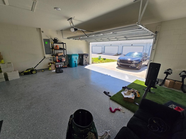 garage with a garage door opener, concrete block wall, and electric panel