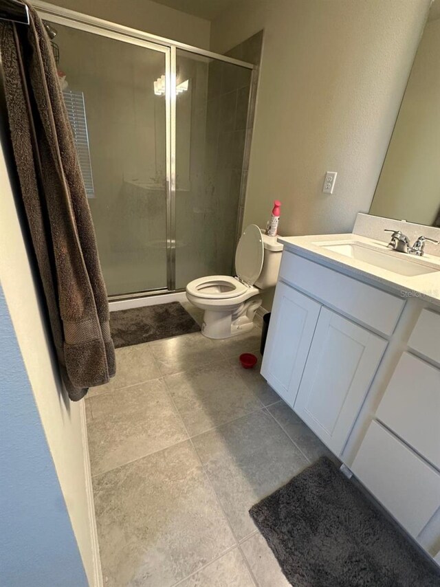 bathroom with a stall shower, tile patterned flooring, vanity, and toilet