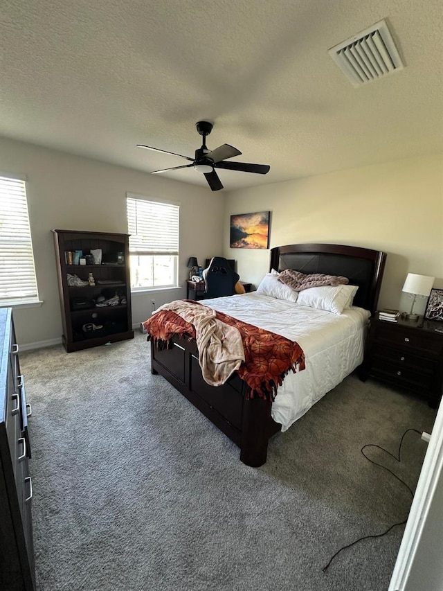 carpeted bedroom with a ceiling fan, visible vents, and a textured ceiling