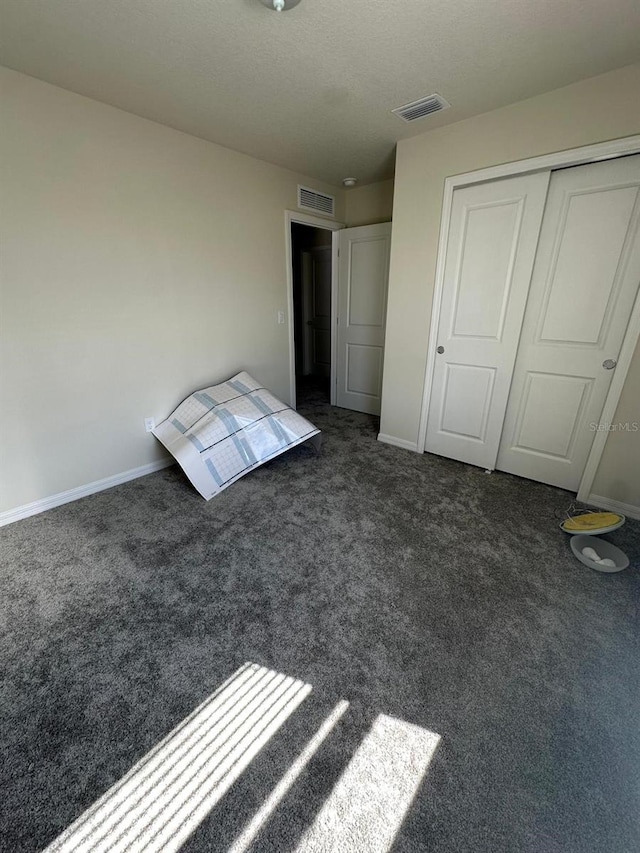 unfurnished bedroom featuring carpet floors, baseboards, visible vents, and a closet