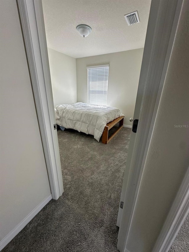 bedroom with carpet floors, baseboards, visible vents, and a textured ceiling