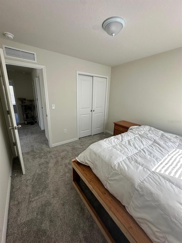 carpeted bedroom with baseboards, a textured ceiling, visible vents, and a closet