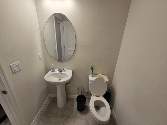 half bath with tile patterned flooring, toilet, and baseboards