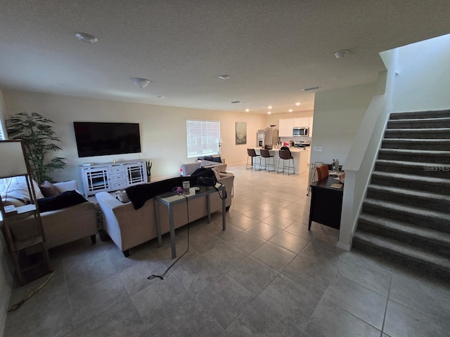 tiled living room with a textured ceiling and stairway