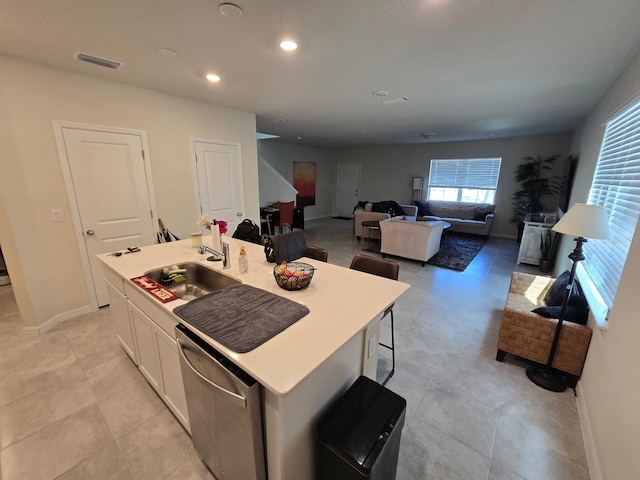 kitchen featuring visible vents, stainless steel dishwasher, white cabinets, a sink, and baseboards