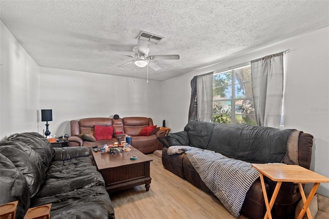 living area featuring light wood-style floors, visible vents, a textured ceiling, and a ceiling fan