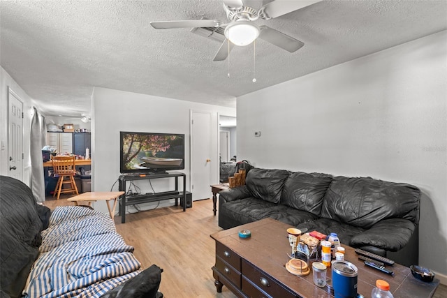 living area with a ceiling fan, light wood-style flooring, and a textured ceiling