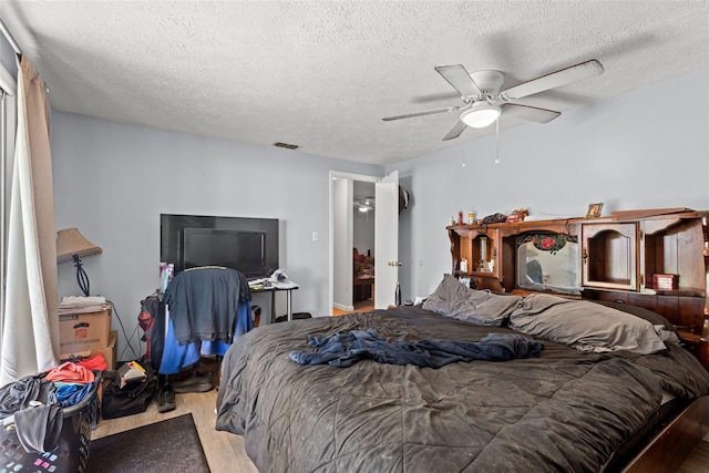 bedroom featuring a textured ceiling, visible vents, and a ceiling fan