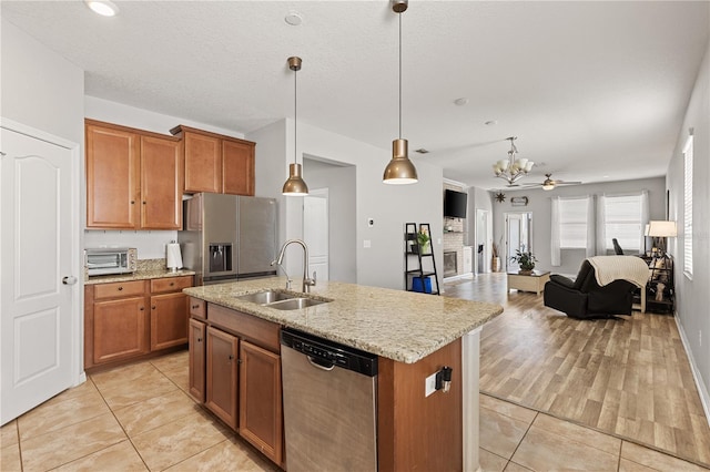 kitchen featuring appliances with stainless steel finishes, brown cabinetry, a sink, and open floor plan