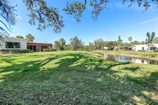 view of yard with a sunroom and a water view