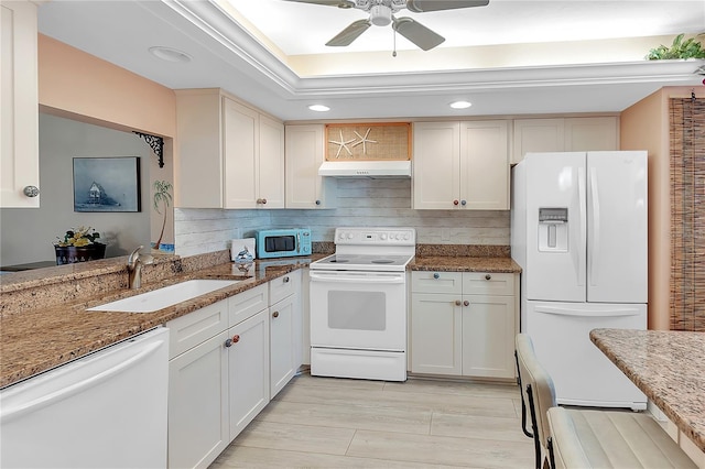 kitchen featuring tasteful backsplash, a sink, dark stone countertops, white appliances, and under cabinet range hood