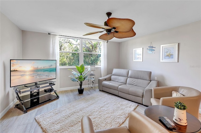 living room featuring ceiling fan, light wood-style flooring, and baseboards