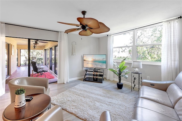 living room with wood finished floors, a ceiling fan, and baseboards