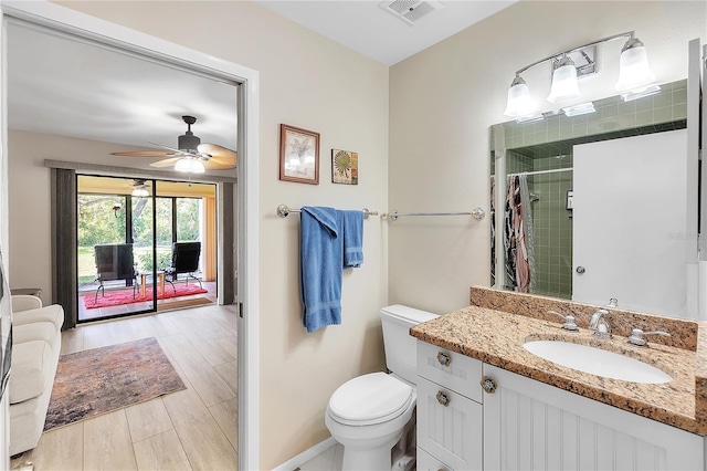 full bathroom featuring wood finish floors, visible vents, toilet, a tile shower, and vanity