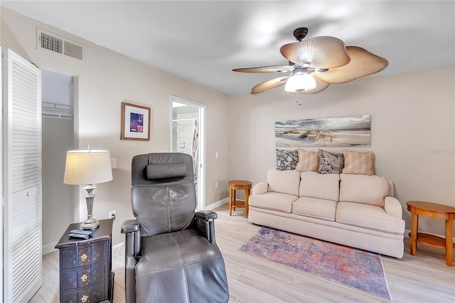 living room with a ceiling fan, visible vents, light wood-style flooring, and baseboards