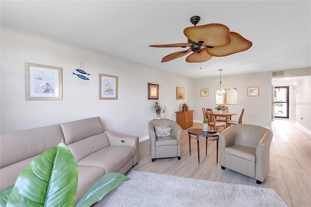 living room featuring a ceiling fan, light wood-style flooring, visible vents, and baseboards