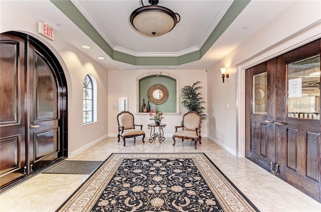 foyer entrance featuring a tray ceiling, baseboards, marble finish floor, and crown molding