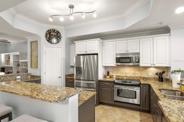 kitchen featuring light stone countertops, a sink, white cabinets, appliances with stainless steel finishes, and tasteful backsplash