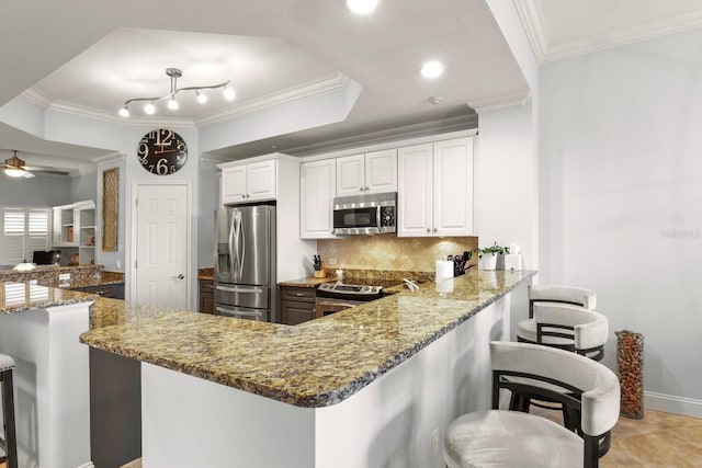kitchen with ornamental molding, stone countertops, tasteful backsplash, appliances with stainless steel finishes, and a breakfast bar area