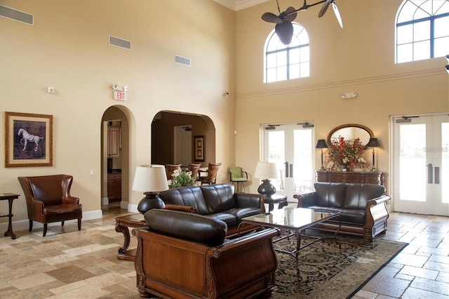living room featuring baseboards, arched walkways, visible vents, and stone tile flooring