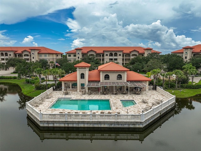 rear view of property featuring a tiled roof, a water view, fence, and a patio area