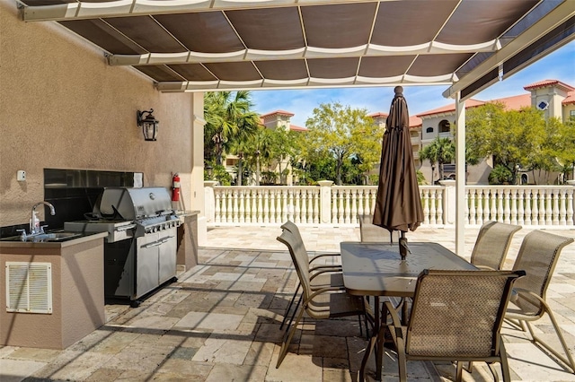 view of patio featuring outdoor dining space, a sink, a pergola, and area for grilling
