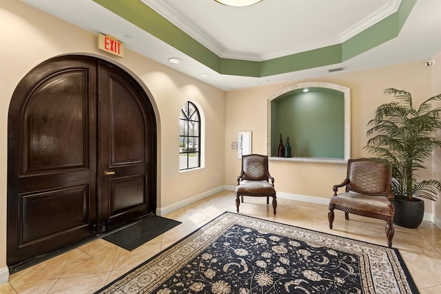 sitting room featuring arched walkways, a raised ceiling, baseboards, and ornamental molding