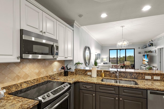 kitchen with a sink, stainless steel appliances, crown molding, open floor plan, and backsplash