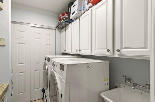 washroom featuring cabinet space, washing machine and dryer, ornamental molding, and a sink
