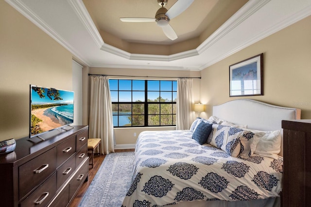 bedroom featuring crown molding, a raised ceiling, a ceiling fan, and dark wood-style flooring