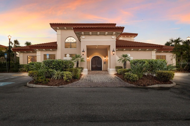 mediterranean / spanish home featuring a tiled roof and stucco siding