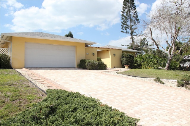 view of front facade featuring a garage, a front yard, and stucco siding