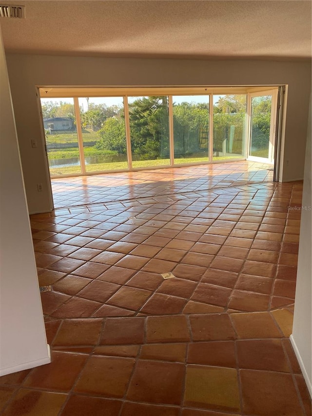 spare room featuring a healthy amount of sunlight, visible vents, and a textured ceiling