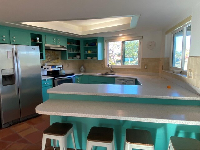 kitchen featuring stainless steel appliances, green cabinetry, a sink, and open shelves