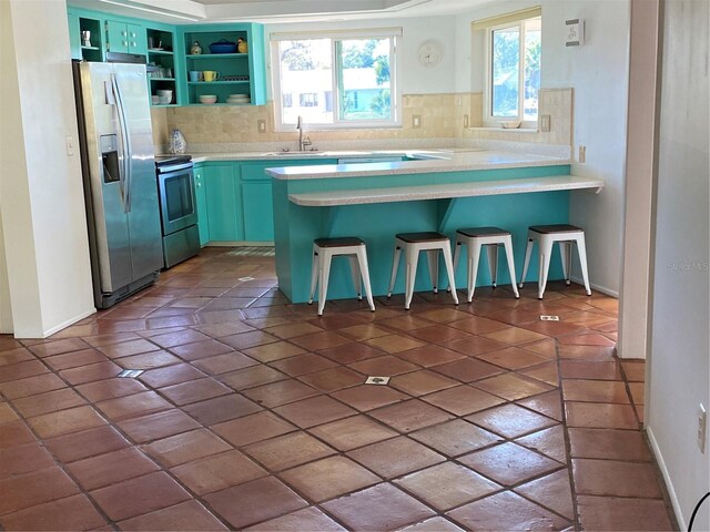 kitchen featuring appliances with stainless steel finishes, open shelves, a sink, and light countertops