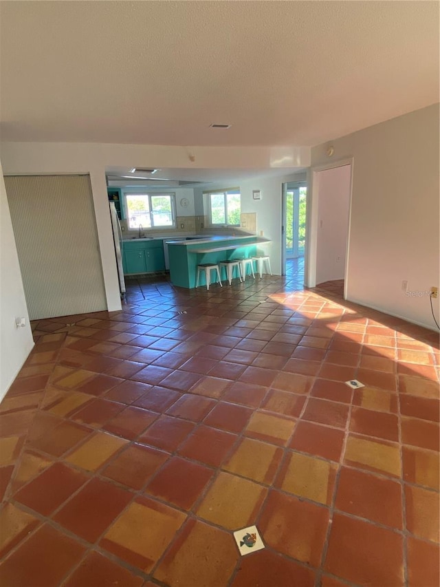 kitchen with tile patterned floors, a kitchen breakfast bar, a textured ceiling, and freestanding refrigerator