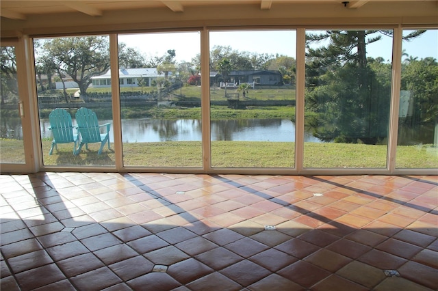 unfurnished sunroom featuring a water view and beam ceiling