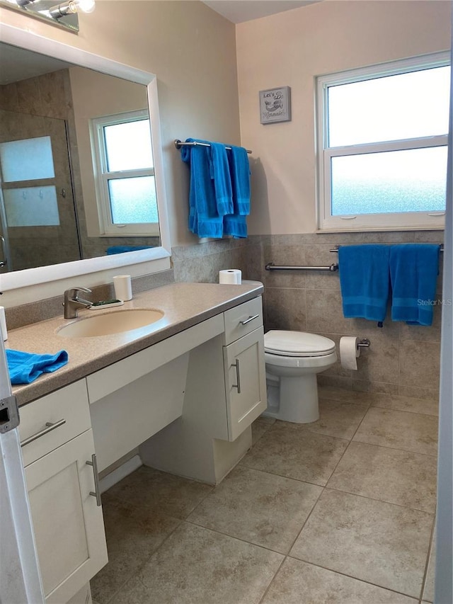 bathroom featuring tile patterned flooring, toilet, vanity, tile walls, and a shower stall