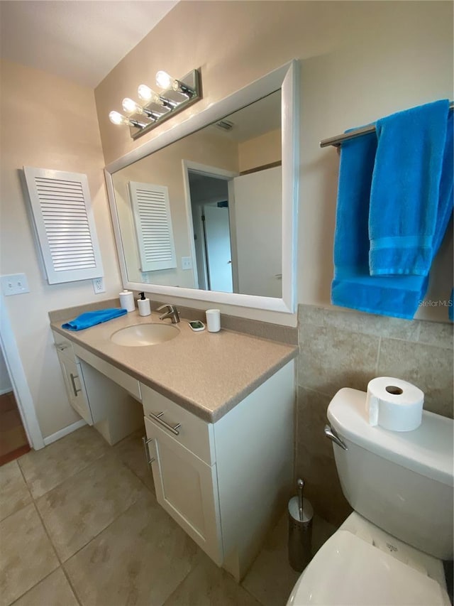 bathroom featuring tile patterned flooring, toilet, visible vents, vanity, and tile walls