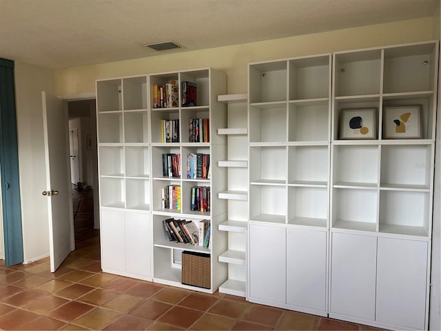 unfurnished room with dark tile patterned flooring, visible vents, and a textured ceiling