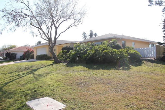 single story home featuring driveway, an attached garage, fence, a front lawn, and stucco siding