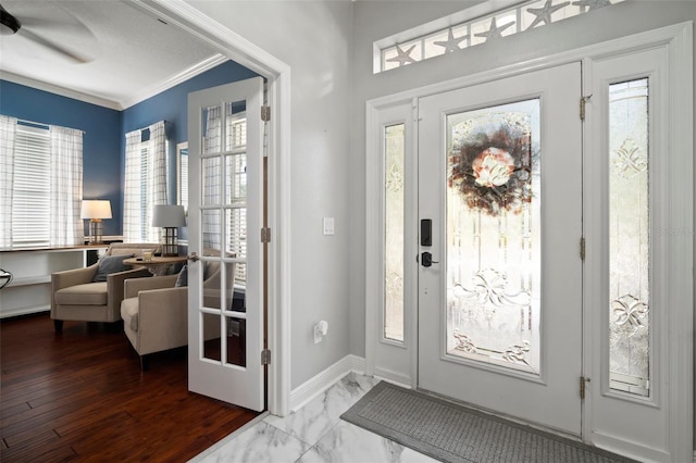 foyer featuring baseboards, marble finish floor, and ornamental molding