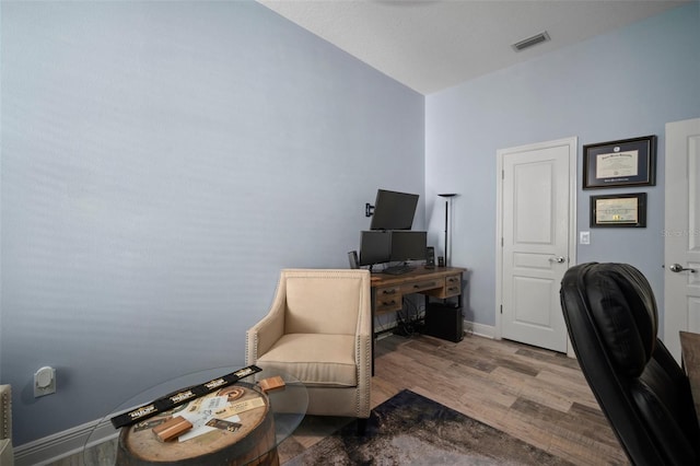 office area with wood finished floors, visible vents, and baseboards