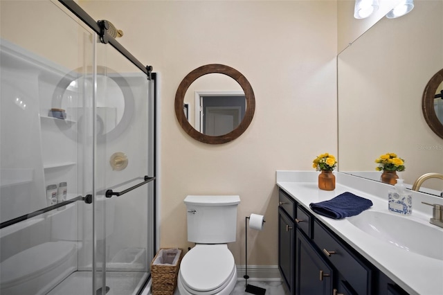 full bathroom with vanity, a shower stall, toilet, and baseboards